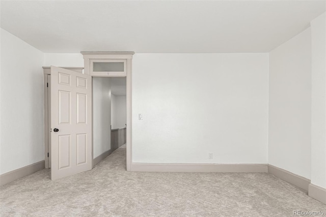 unfurnished room featuring light carpet and baseboards