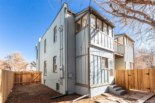 view of side of home featuring a fenced backyard, a gate, and brick siding