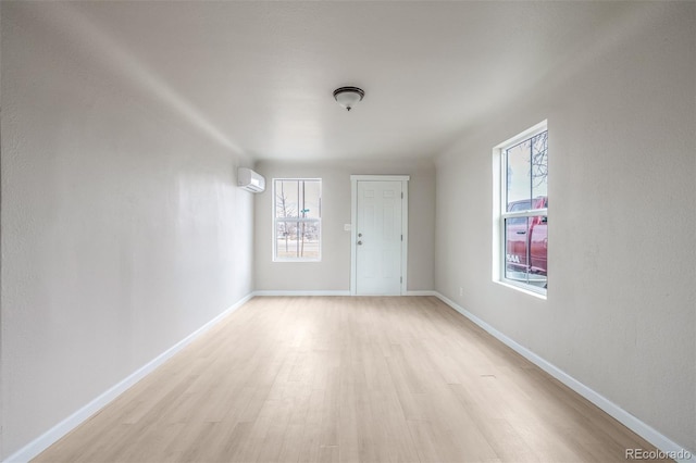 unfurnished room with plenty of natural light, a wall mounted AC, and light wood-type flooring