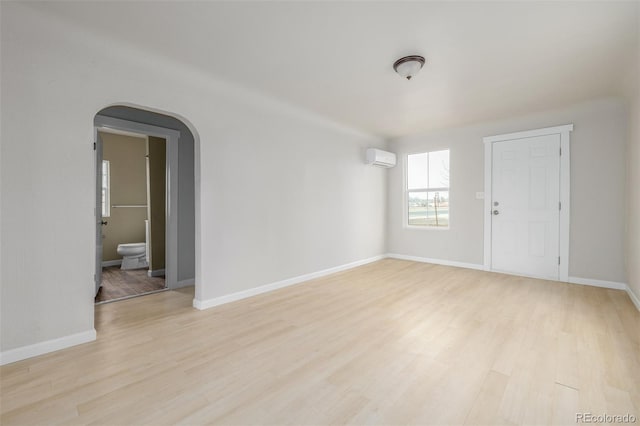 spare room with a wall unit AC and light hardwood / wood-style floors