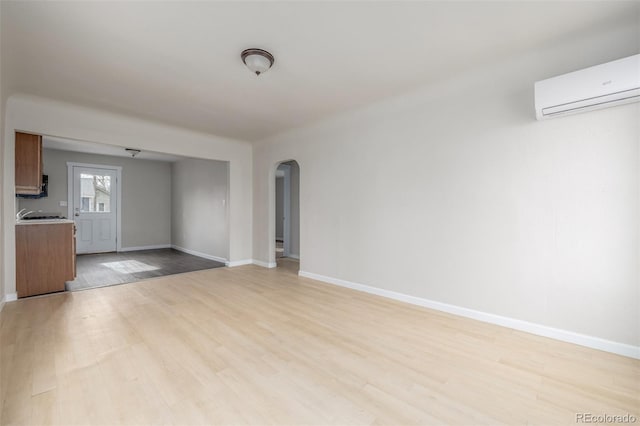 unfurnished living room with light wood-type flooring and an AC wall unit