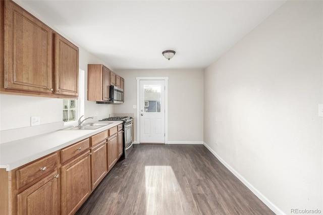 kitchen with appliances with stainless steel finishes, sink, and dark wood-type flooring