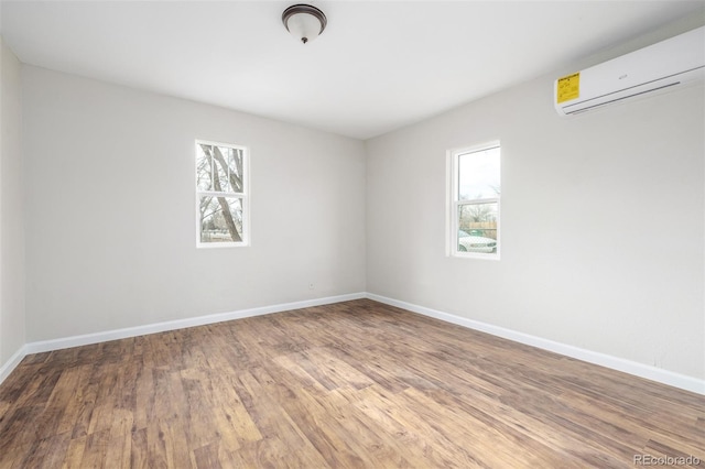 unfurnished room with hardwood / wood-style floors, plenty of natural light, and an AC wall unit