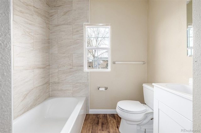 bathroom featuring vanity, hardwood / wood-style flooring, a bathing tub, and toilet