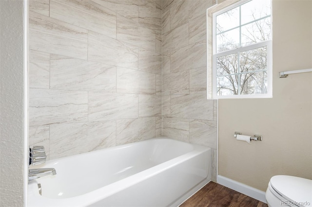 bathroom with a washtub, hardwood / wood-style floors, and toilet