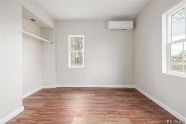 spare room with dark hardwood / wood-style floors, a wealth of natural light, and an AC wall unit