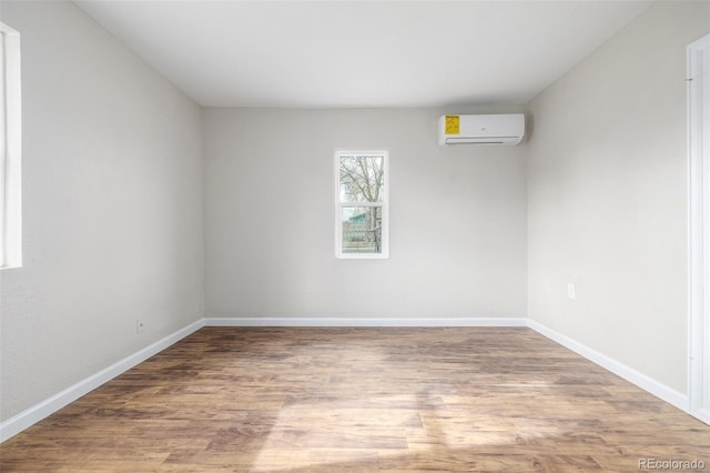 unfurnished room featuring wood-type flooring and an AC wall unit