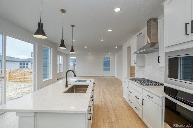 23708 E 42nd Ave, Aurora, CO 80019 - kitchen with appliances with stainless steel finishes, a sink, wall chimney range hood, light wood-style floors, and a center island with sink