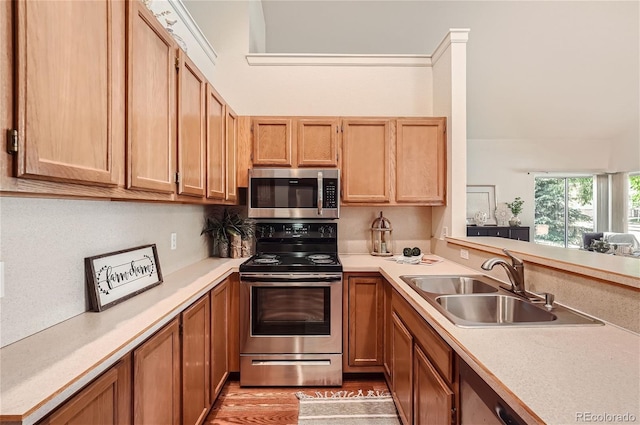 kitchen featuring stainless steel appliances, a sink, light countertops, and light wood-type flooring