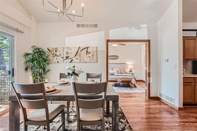 dining area featuring wood finished floors, lofted ceiling, a chandelier, and baseboards