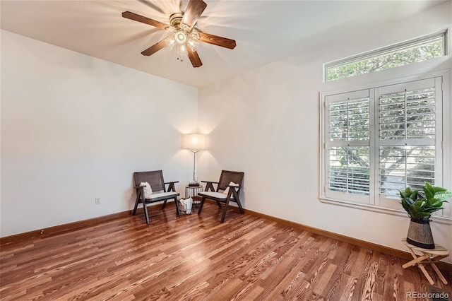 living area featuring wood finished floors, ceiling fan, and baseboards