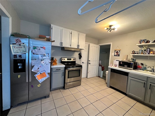 kitchen with sink, light tile patterned floors, gray cabinets, white cabinets, and appliances with stainless steel finishes