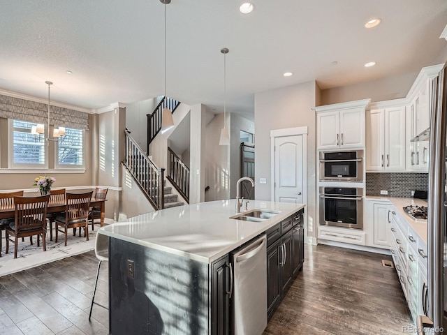 kitchen featuring dark wood-style floors, stainless steel appliances, an inviting chandelier, and a sink