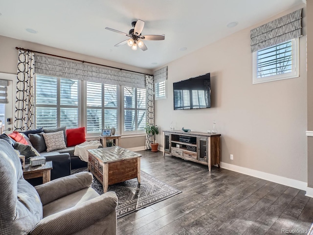 living room featuring a healthy amount of sunlight, baseboards, dark wood-type flooring, and a ceiling fan