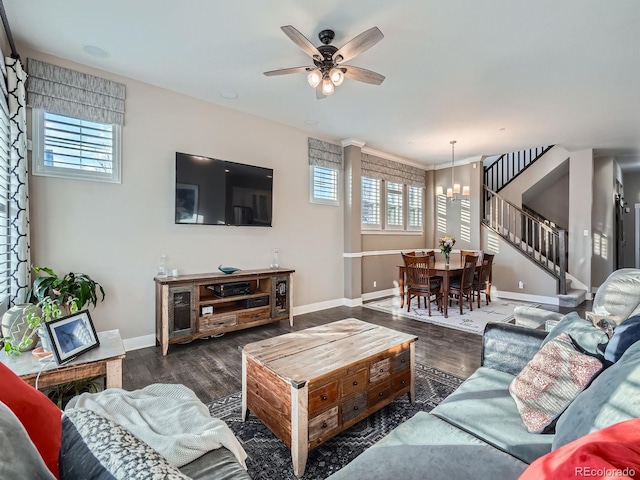 living room featuring baseboards, wood finished floors, stairs, and ceiling fan with notable chandelier