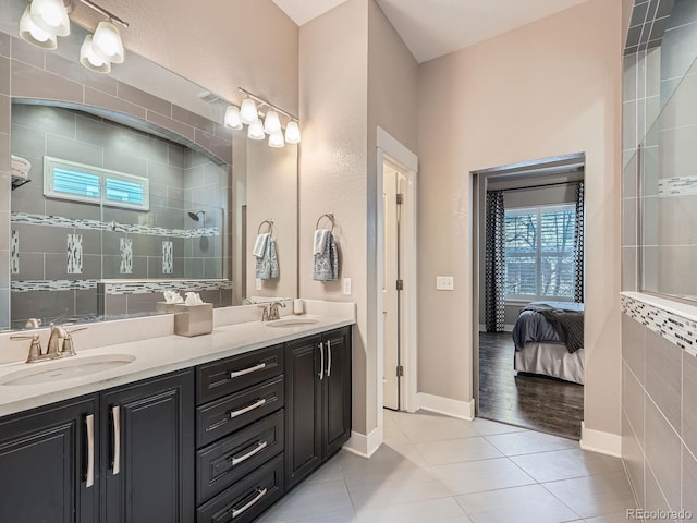 bathroom featuring a sink, tiled shower, double vanity, and tile patterned floors