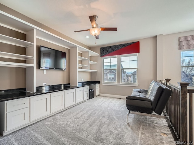 sitting room with light carpet, a healthy amount of sunlight, baseboards, and ceiling fan