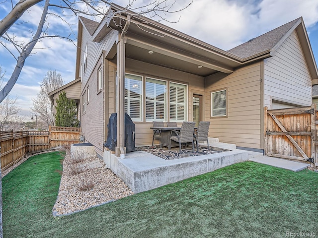 back of house with a patio, a lawn, fence private yard, and a gate