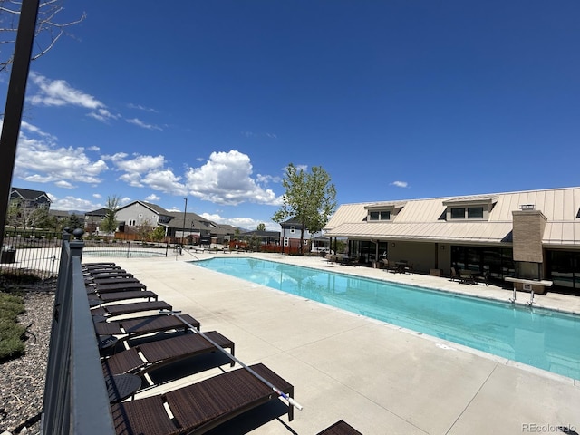 community pool with a residential view, a patio, and fence