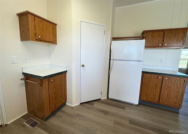 15125 Ewing Ct, Peyton, CO 80831 - kitchen featuring freestanding refrigerator, dark wood-style floors, brown cabinetry, and dark countertops