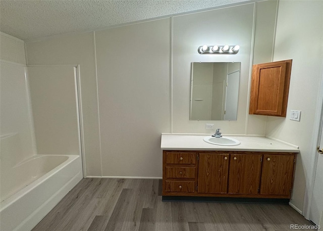 15125 Ewing Ct, Peyton, CO 80831 - bathroom with wood finished floors, vanity, a textured ceiling, and shower / washtub combination
