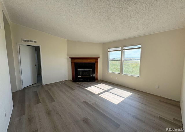 15125 Ewing Ct, Peyton, CO 80831 - unfurnished living room featuring wood finished floors, a textured ceiling, a fireplace with flush hearth, and lofted ceiling
