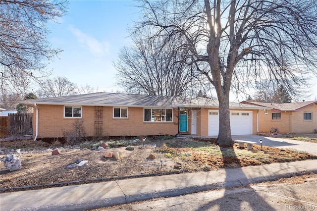 single story home with a garage, concrete driveway, brick siding, and fence