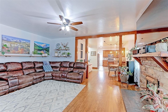 living room featuring ceiling fan, a fireplace, and light hardwood / wood-style floors