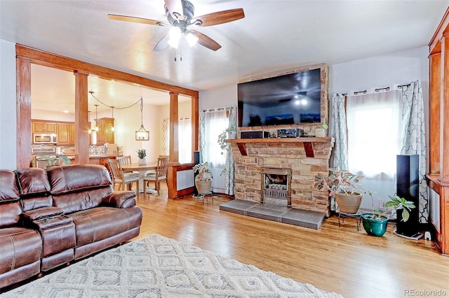 living room with ceiling fan, plenty of natural light, a large fireplace, and light hardwood / wood-style floors