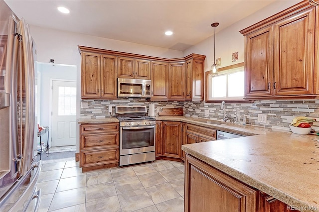 kitchen with pendant lighting, sink, backsplash, and appliances with stainless steel finishes