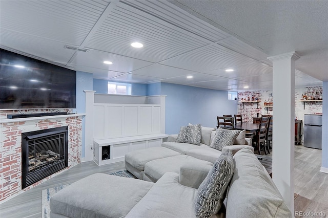 living room featuring a brick fireplace and light wood-type flooring