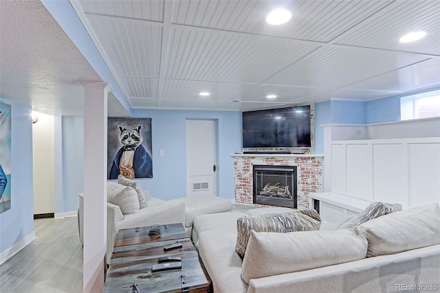 living room with light hardwood / wood-style floors, a brick fireplace, and wooden ceiling