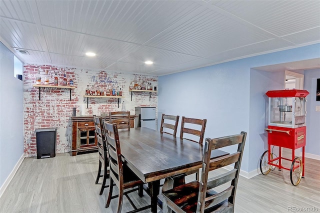 dining space featuring brick wall and light hardwood / wood-style floors