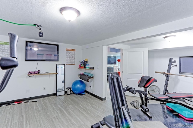 exercise area with light hardwood / wood-style flooring and a textured ceiling