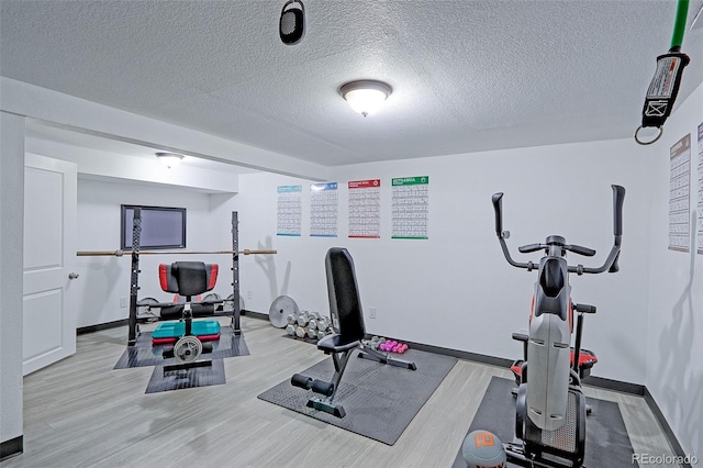 exercise room featuring a textured ceiling and light wood-type flooring