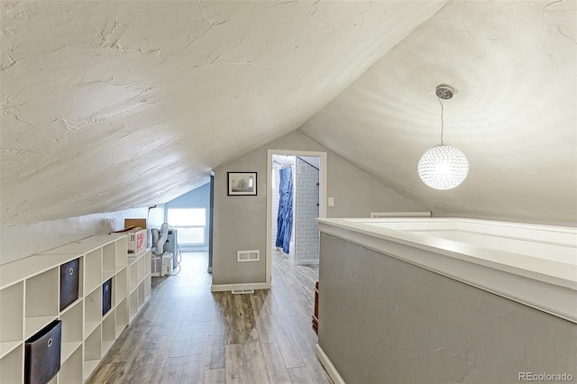 additional living space with wood-type flooring and vaulted ceiling