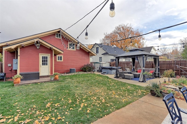 rear view of property featuring a lawn, a gazebo, a patio, a hot tub, and central air condition unit