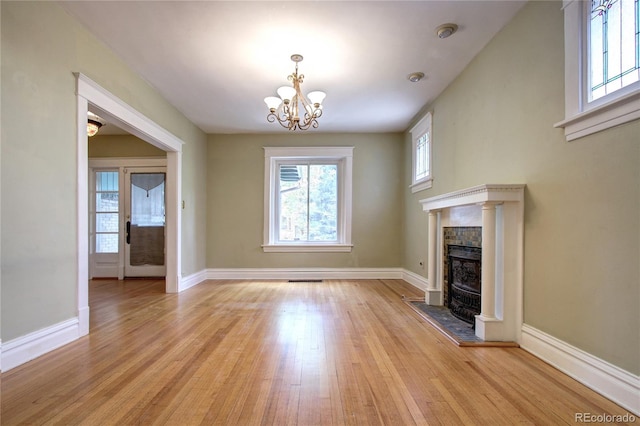 unfurnished living room featuring a notable chandelier and light wood-type flooring