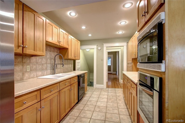 kitchen featuring tasteful backsplash, light tile patterned floors, sink, and black appliances