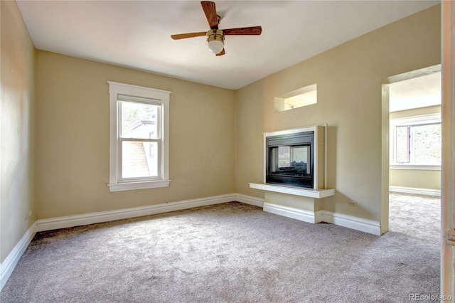 unfurnished living room featuring light colored carpet, ceiling fan, and a multi sided fireplace