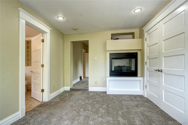 unfurnished living room featuring light carpet and a multi sided fireplace