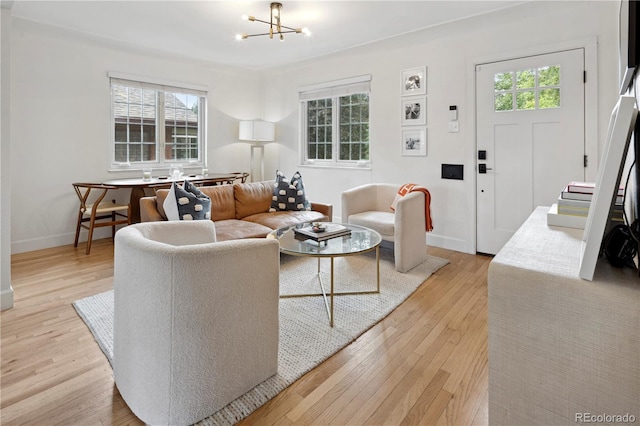 living room featuring light wood-type flooring, an inviting chandelier, and plenty of natural light