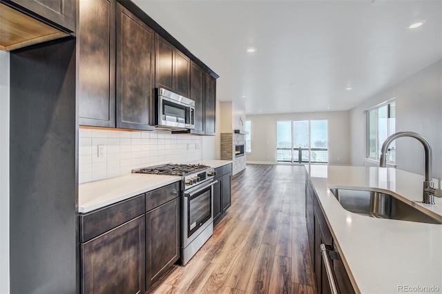 kitchen featuring tasteful backsplash, dark brown cabinetry, stainless steel appliances, sink, and light hardwood / wood-style floors