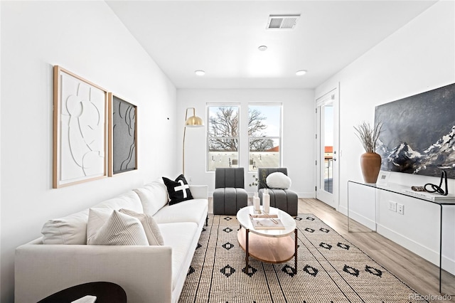 living area with light wood-style flooring, visible vents, and baseboards