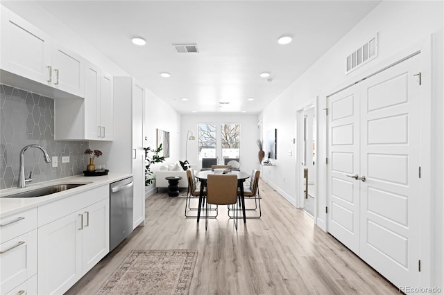 kitchen with a sink, light wood-style flooring, visible vents, and stainless steel dishwasher