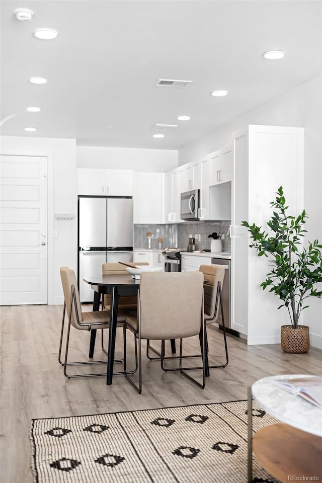 dining space with light wood-style floors, visible vents, and recessed lighting