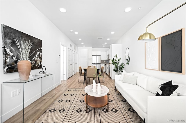 living room with baseboards, light wood-style floors, visible vents, and recessed lighting