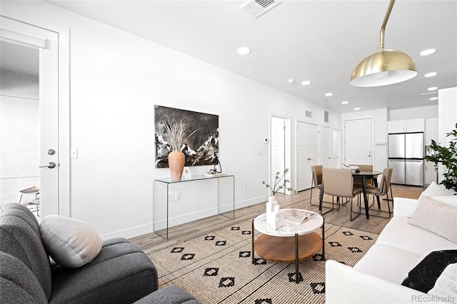 living room featuring recessed lighting, baseboards, visible vents, and light wood finished floors