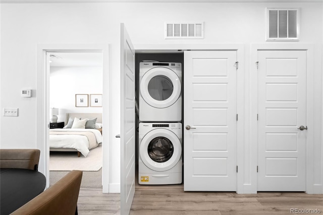 laundry room featuring light wood-style floors, stacked washer / dryer, and visible vents