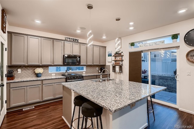 kitchen featuring a sink, a kitchen breakfast bar, gray cabinetry, and stainless steel appliances